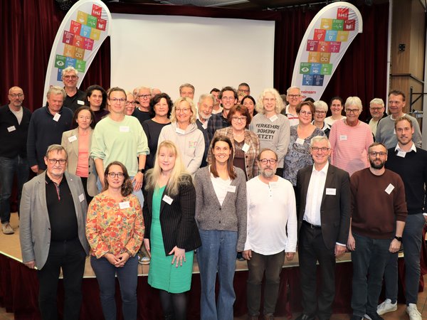 Gruppe von vielen Menschen vor und auf einer Bühne