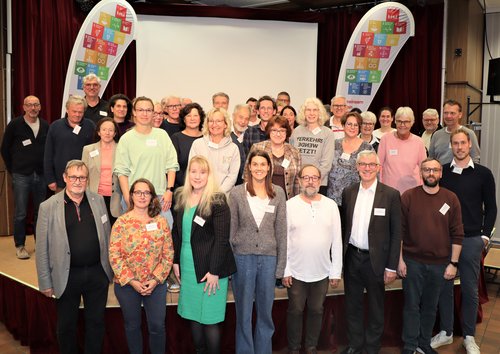 Gruppe von vielen Menschen vor und auf einer Bühne