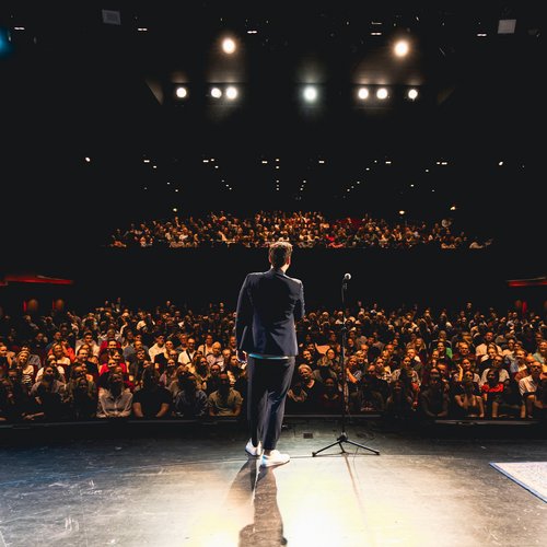 Einzelner Mensch auf einer Bühne vor dem Publikum