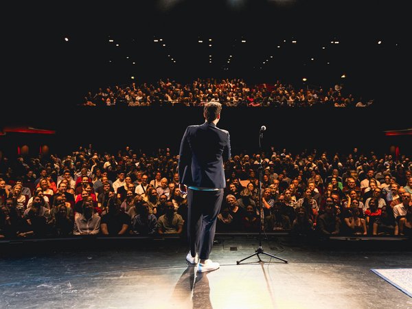 Einzelner Mensch auf einer Bühne vor dem Publikum