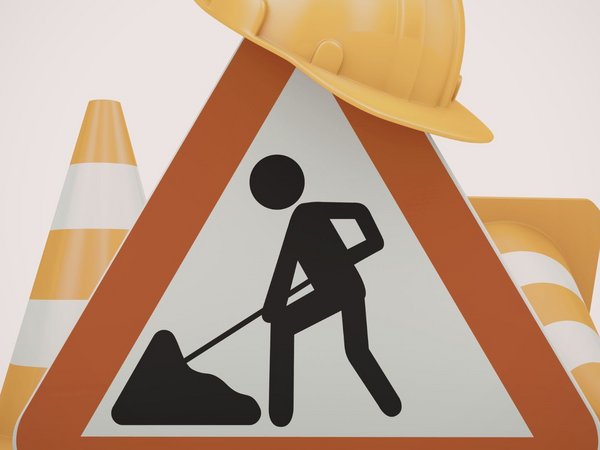 Baustellenschild mit Bauhelm und Kegeln 