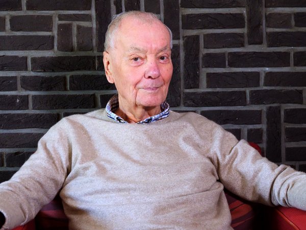 Älterer Mann vor geklinkerter Mauer
