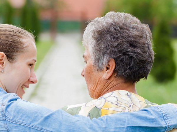 Junge Frau legt älterer Frau den Arm um die Schultern 