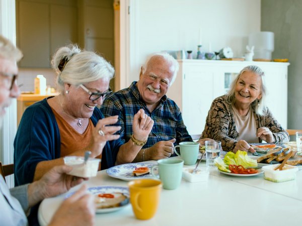 Mehrere ältere Personen sitzen an einem gedeckten Frühstückstisch