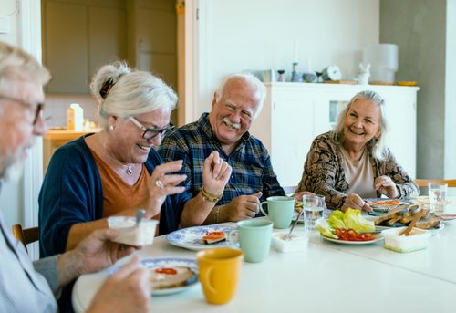 Mehrere ältere Personen sitzen an einem gedeckten Frühstückstisch