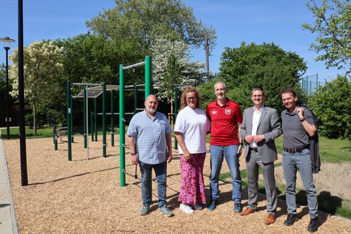 Personengruppe stehen vor einer Sportanlage mit Geräten