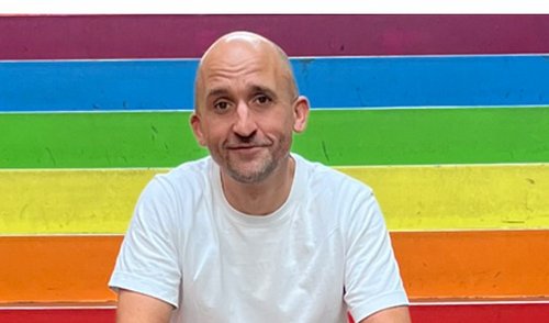 Mann vor einer Regenbogenfahne