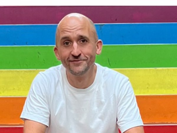 Mann vor einer Regenbogenfahne