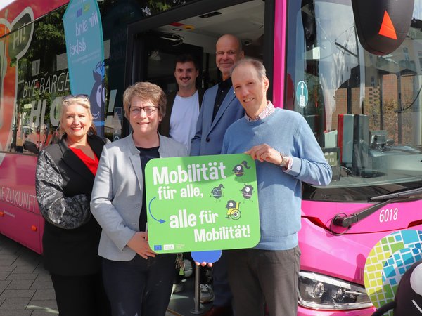 Personengruppe mit Plakat in einer Bustür