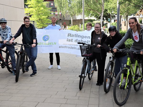 Mehrere junge Leute mit Fahrrädern und einem Banner