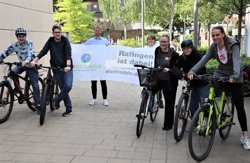 Mehrere junge Leute mit Fahrrädern und einem Banner