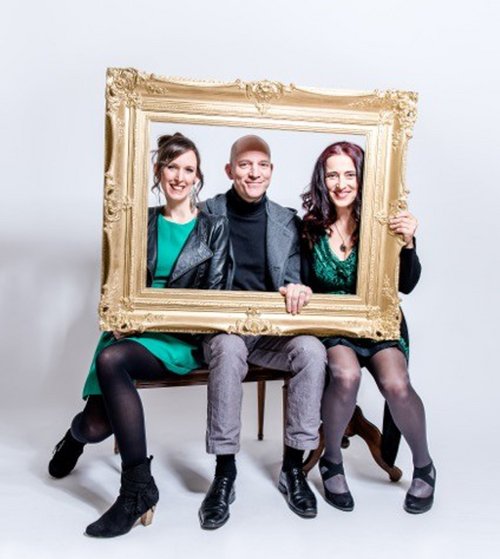 Drei Personen schauen durch einen vergoldeten Bilderrahmen