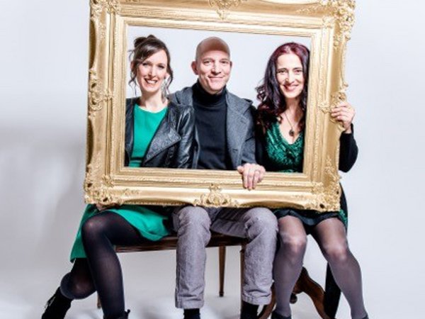 Drei Personen schauen durch einen vergoldeten Bilderrahmen