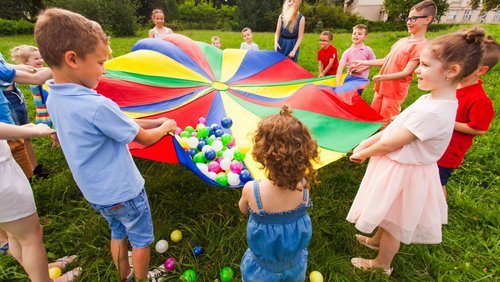 Kinder stehen im Kreis und halten ein buntes Tuch 