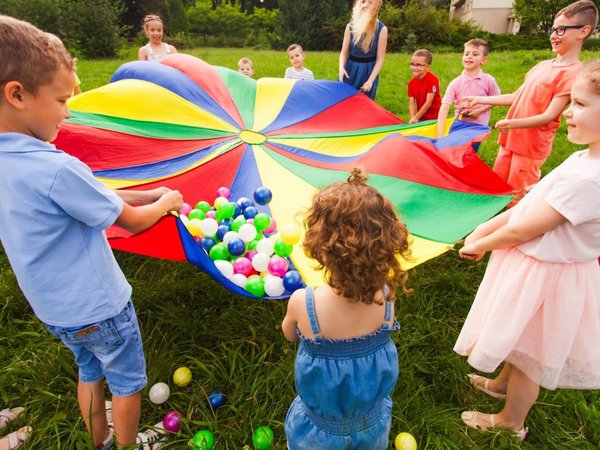 Kinder stehen im Kreis und halten ein buntes Tuch 