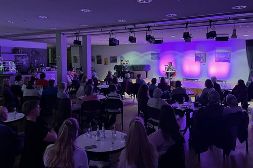 gefüllter Saal und eine Bühne
