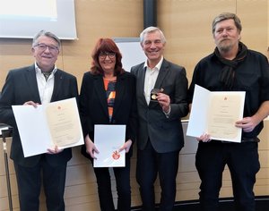 Vier Personen zeigen Urkunden