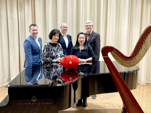 Mehrere Personen an einem Flügel, daneben eine Harfe