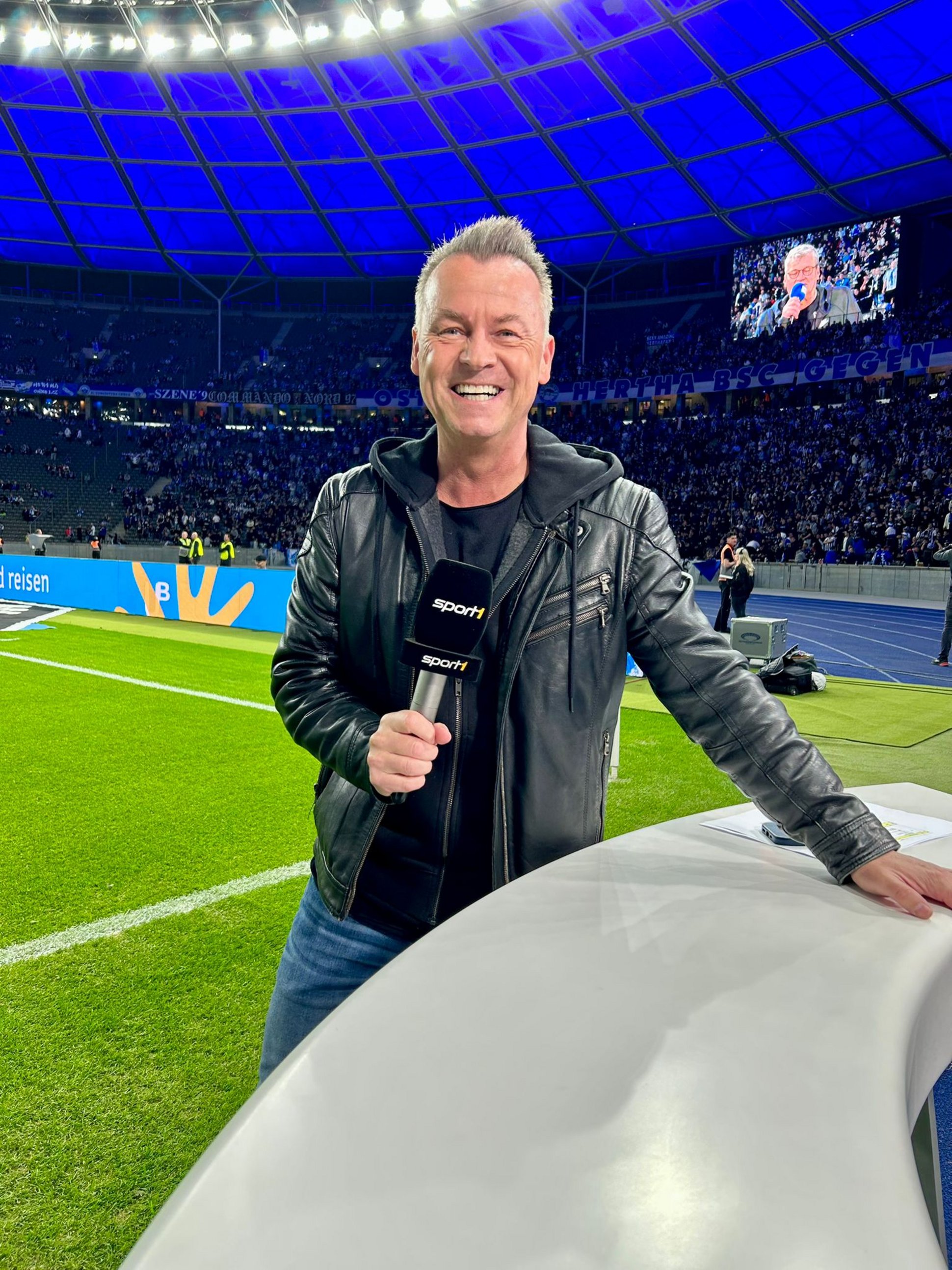 Oliver Forster mit Mikro im Stadion am Spielfeldrand