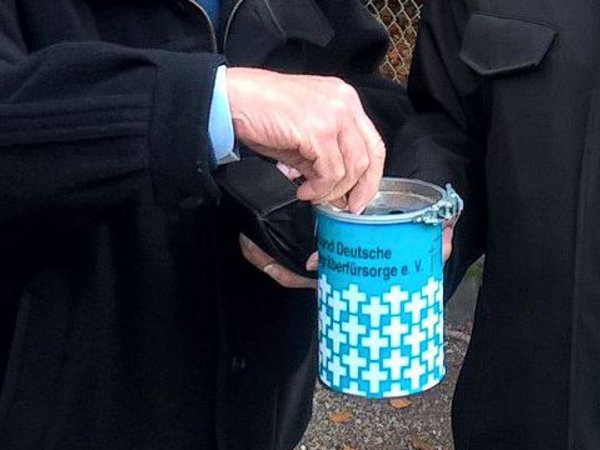 Hand wirft Geld in eine Sammelbüchse.