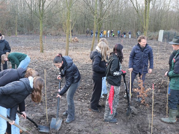 Mehrere Mädchen mit Spaten, daneben zwei Männer im Gespräch