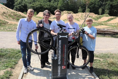 Mehrere Personen mit Fahrrad an der Reparaturstation  