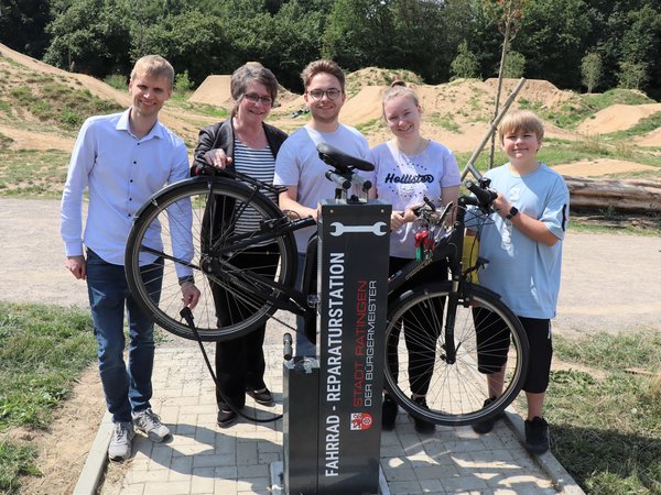 Mehrere Personen mit Fahrrad an der Reparaturstation  