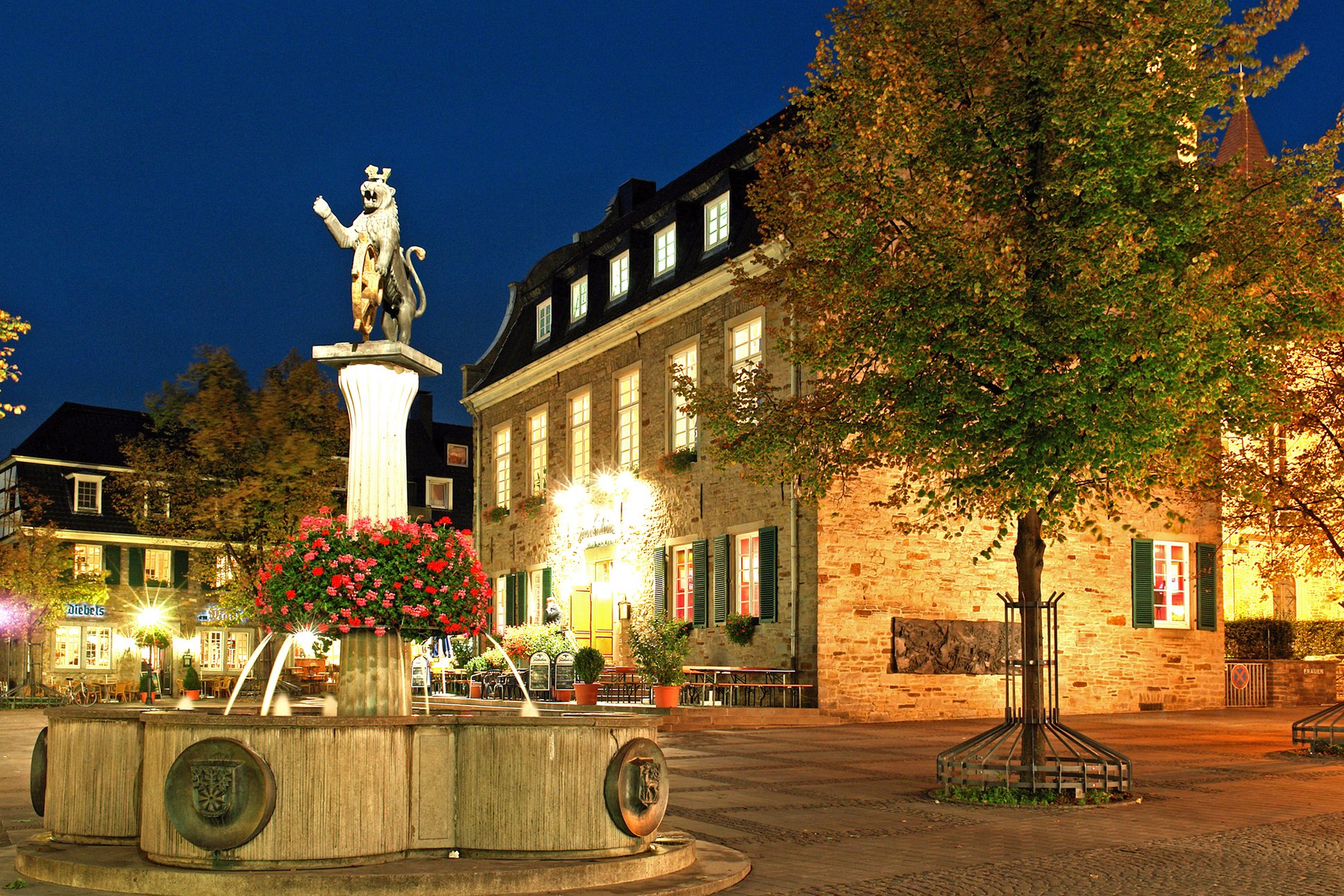 Beleuchteter Brunnen und Bürgerhaus auf dem Marktplatz. 