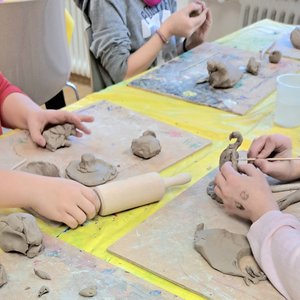 Kinderhände modellieren Figuren aus Ton