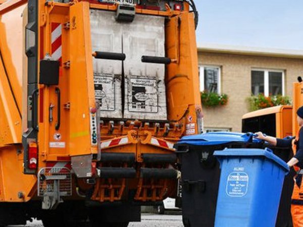 Mann mit zwei Mülltonnen vor einem Müllwagen