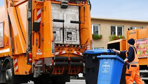 Mann mit zwei Mülltonnen vor einem Müllwagen