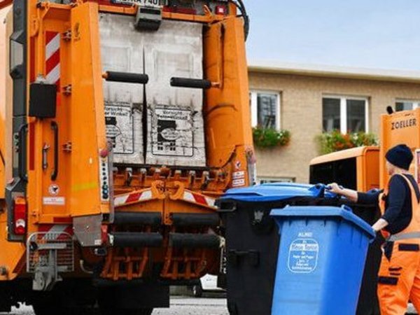 Mann mit zwei Mülltonnen vor einem Müllwagen