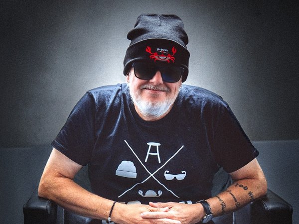 Mann mit Pudelmütze und Sonnenbrille sitzt in einem Sessel
