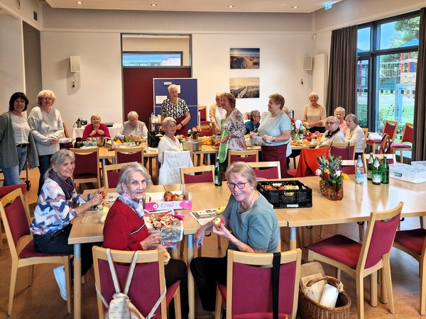 Mehrere ältere Frauen bereiten gemeinsam an Tischen Obst und Gemüse zu.