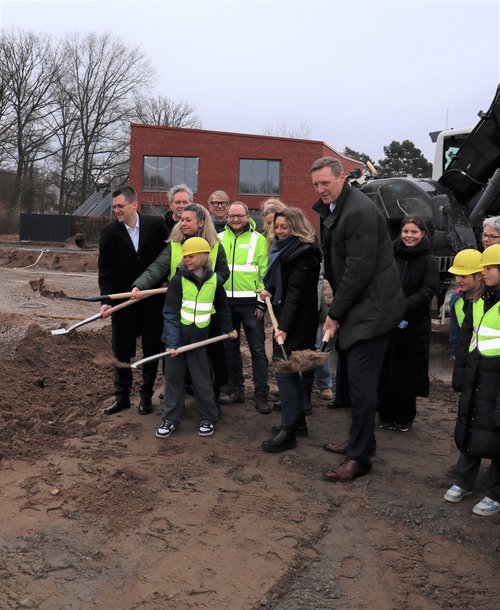 Mehrere Personen mit Schaufeln auf einem Baufeld