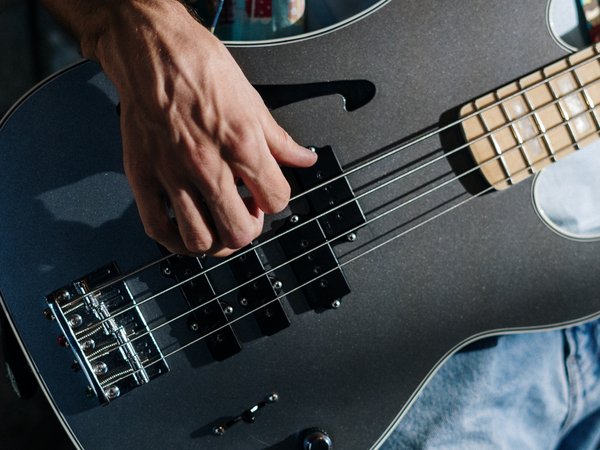 Hand zupft an einer Gitarrensaite 