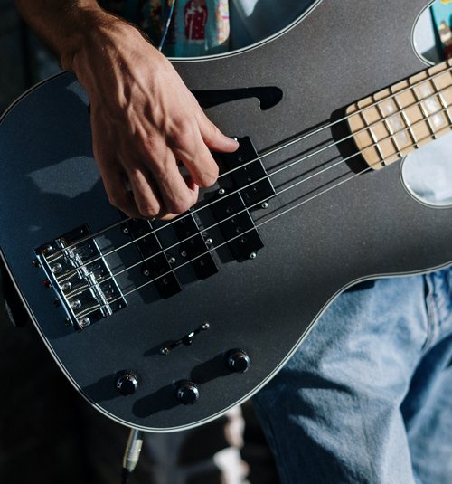 Hand zupft an einer Gitarrensaite 