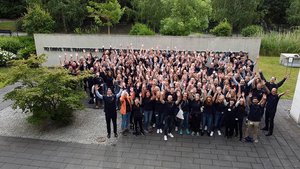 Eine große Gruppe von DKV-Mobility Mitarbeitenden stehen gut gelaunt beisammen.