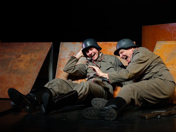 Bühnenszene mit zwei Soldaten, die auf dem Boden liegen