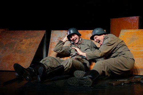 Bühnenszene mit zwei Soldaten, die auf dem Boden liegen