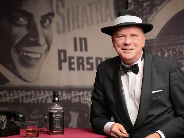 Mann mit Hut an einem Stehtisch