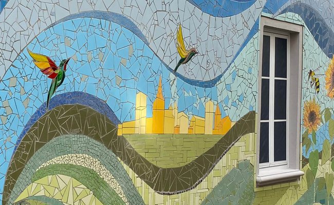 Buntes Mosaik mit floralen Elementen auf einer Hauswand