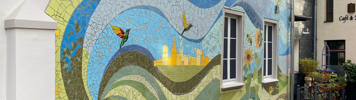 Buntes Mosaik mit floralen Elementen auf einer Hauswand