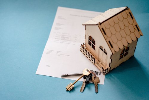 Symbolbild: Miniatur-Holzhaus und Wohnungsschlüssel