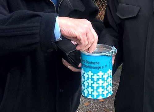 Hand wirft Geld in eine Sammelbüchse.