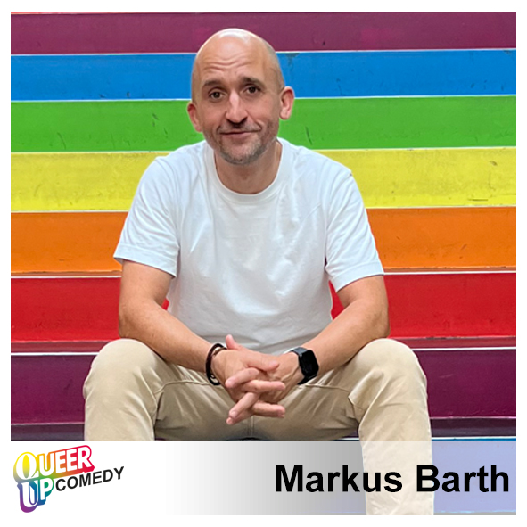 Markus Barth, sitzend vor einer Regenbogenfahne